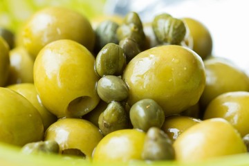 Green olives and capers in bowl, closeup, Italian ingredients