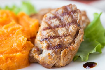 Pork steak fried on grill with mashed sweet potatoes, tasty
