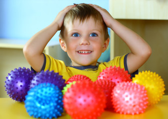 Fototapeta na wymiar A boy plays with rubber colored balls