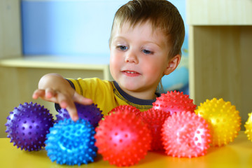 Fototapeta na wymiar A boy plays with rubber colored balls