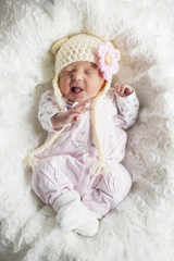 Newborn M&auml;dchen mit s&uuml;&szlig;er M&uuml;tze verzieht den Mund