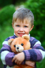 Smiling boy with a soft toy teddy bear