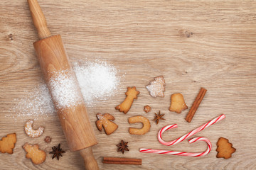 Rolling pin with flour, spices and cookies on wooden table