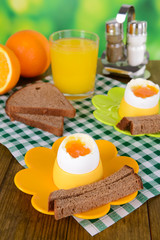 Boiled eggs in egg cups on table on bright background