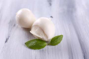 Tasty mozzarella cheese with basil, on wooden table