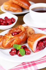Fresh baked pasties with cherry on plate on table close-up