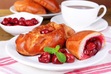 Fresh baked pasties with cherry on plate on table close-up