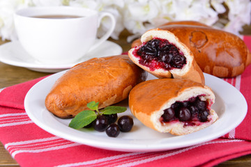 Fresh baked pasties with currant on plate on table close-up