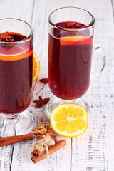 Mulled wine with oranges and spices on wooden background