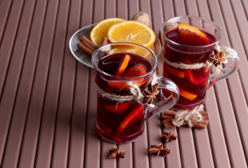 Mulled wine with oranges and spices on wooden background