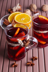 Mulled wine with oranges and spices on wooden background