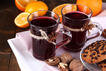 Mulled wine with oranges and cookies on table close up