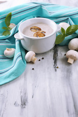 Mushroom soup in white pot, on napkin,  on wooden background