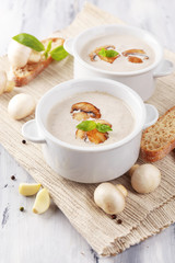 Mushroom soup in white pots, on napkin,  on wooden background
