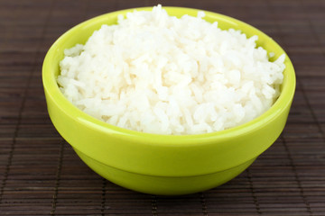 Cooked rice in bowl on bamboo background