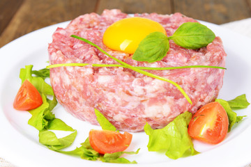 Delicious steak tartare with yolk on plate on table close-up
