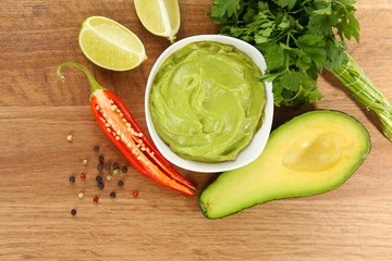Fresh guacamole in bowl on wooden table