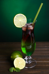 Glass of cocktail on table on dark green background