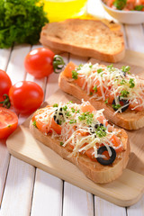 Delicious bruschetta with tomatoes on cutting board close-up