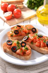 Delicious bruschetta with tomatoes on plate on table close-up