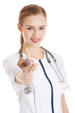 Beautiful caucasian nurse or doctor is holding raw garlic.