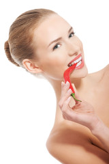 Beautiful caucasian topless woman with chili pepper in mouth.