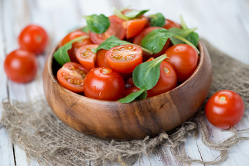 Wooden bowl with fresh cherry tomatoes and corn salad, close-up