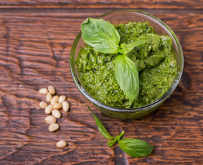 Fresh pesto in small glass bowl on wooden background