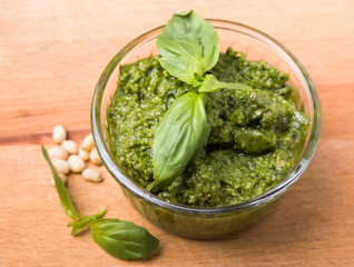 Fresh pesto in small glass bowl on wooden background