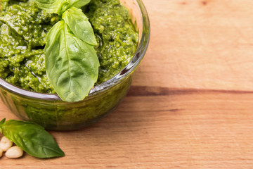 Fresh pesto in small glass bowl on wooden background