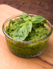 Fresh pesto in small glass bowl on wooden background