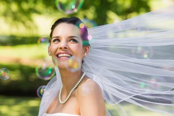 Beautiful bride looking at soap bubbles in park