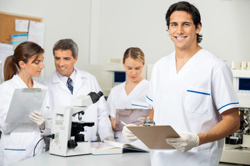 Fototapeta na wymiar Male Scientist Holding Clipboard In Lab