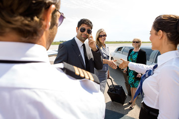Corporate People Greeting Pilot And Airhostess At Airport