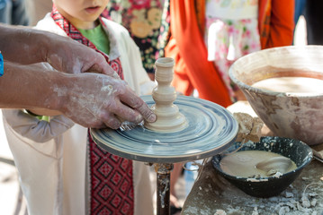 Potter guiding pottery to boy