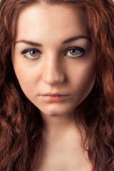 Fototapeta premium Closeup portrait of young woman with red hairs looking at camera