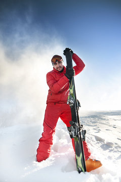 Portrait of young skier on snow with blue sky behind.