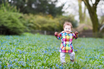 Little baby girl walking in a blue flower field