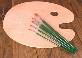 Wooden art palette and brushes on table close-up