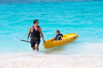 Father and son enjoying a kayak ride on a troical beach