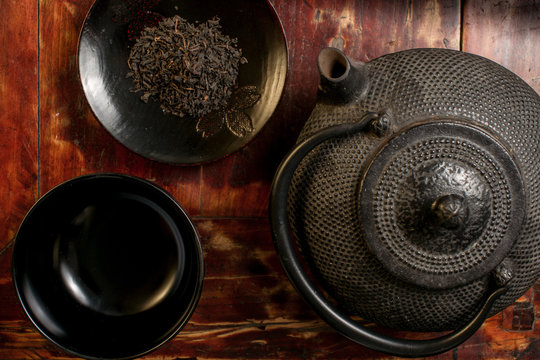 Japanese iron teapot and heap of tea leaves from top.