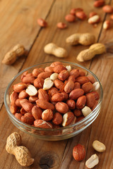 Raw peanuts or groundnuts on wooden table in glass bowl