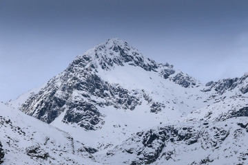 Fototapeta na wymiar Severe mountains peaks covered by snow under dramatic sky