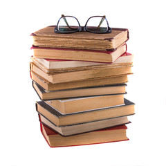 Stack of old antique books and spectacles in thick-rimmed.