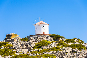 Fototapeta na wymiar old white windmill on a rocky cliff