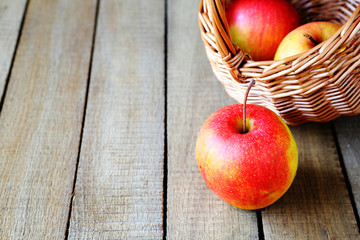 ripe apples and a basket on wooden background
