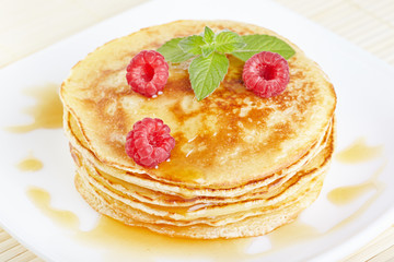 Pancakes with honey, raspberry and a mint branch