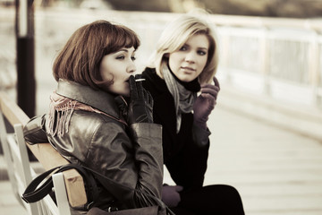 Fototapeta na wymiar Two young women sitting on a bench