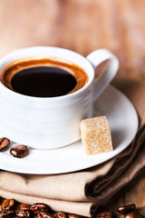 Coffee cup with white saucer and roasted coffee beans  on wooden