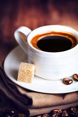 Coffee cup with white saucer and roasted coffee beans  on wooden